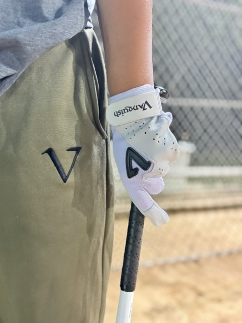 Player holding a bat while wearing a white Vanquish batting glove