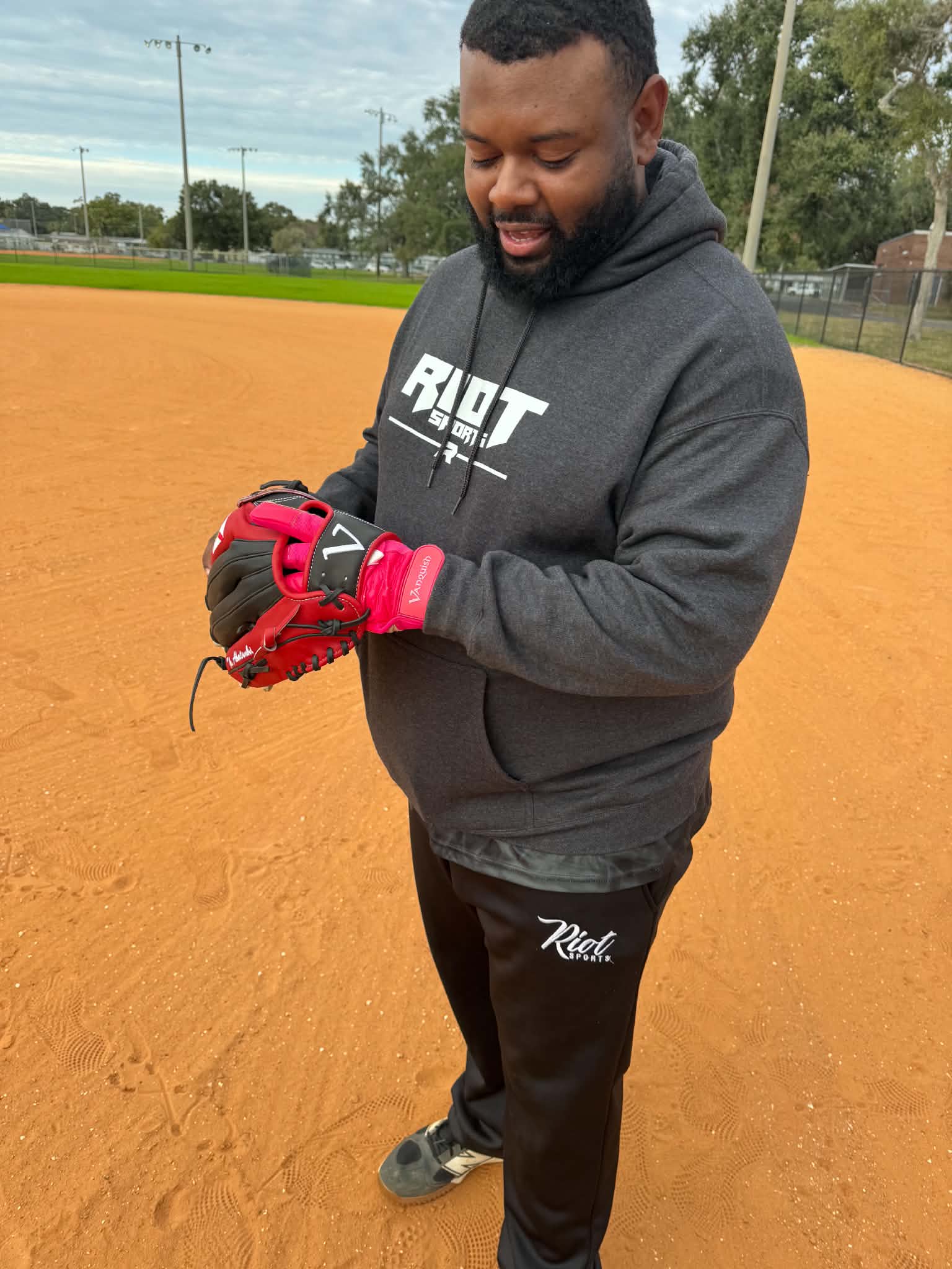 Player wearing a red Vanquish batting glove and holding a custom fielding glove